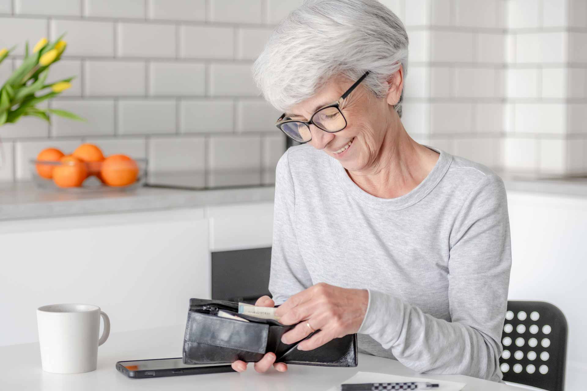 Senior woman smiling while counting cash in her wallet